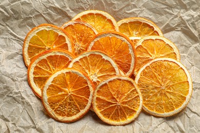 Many dry orange slices on crumpled parchment, flat lay