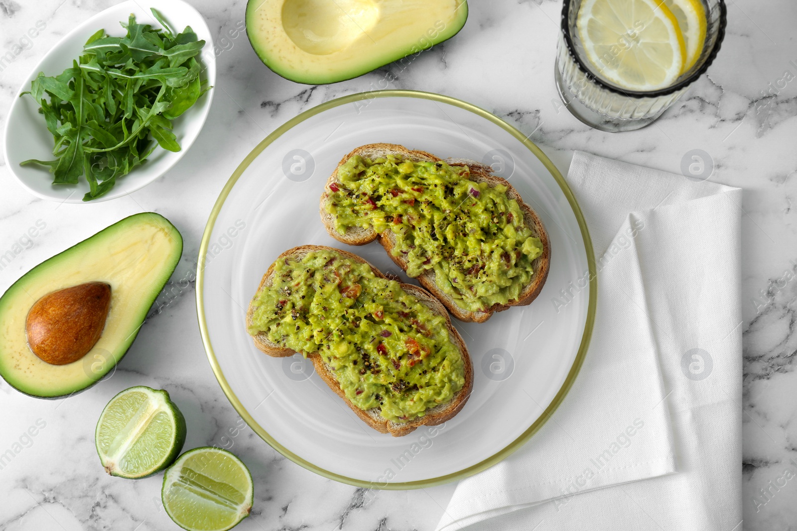 Photo of Delicious sandwiches with guacamole and ingredients on white marble table, flat lay