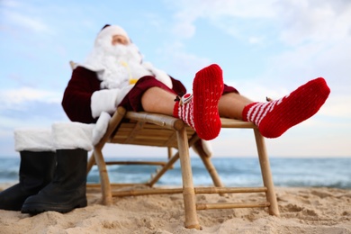 Photo of Santa Claus relaxing on beach. Christmas vacation