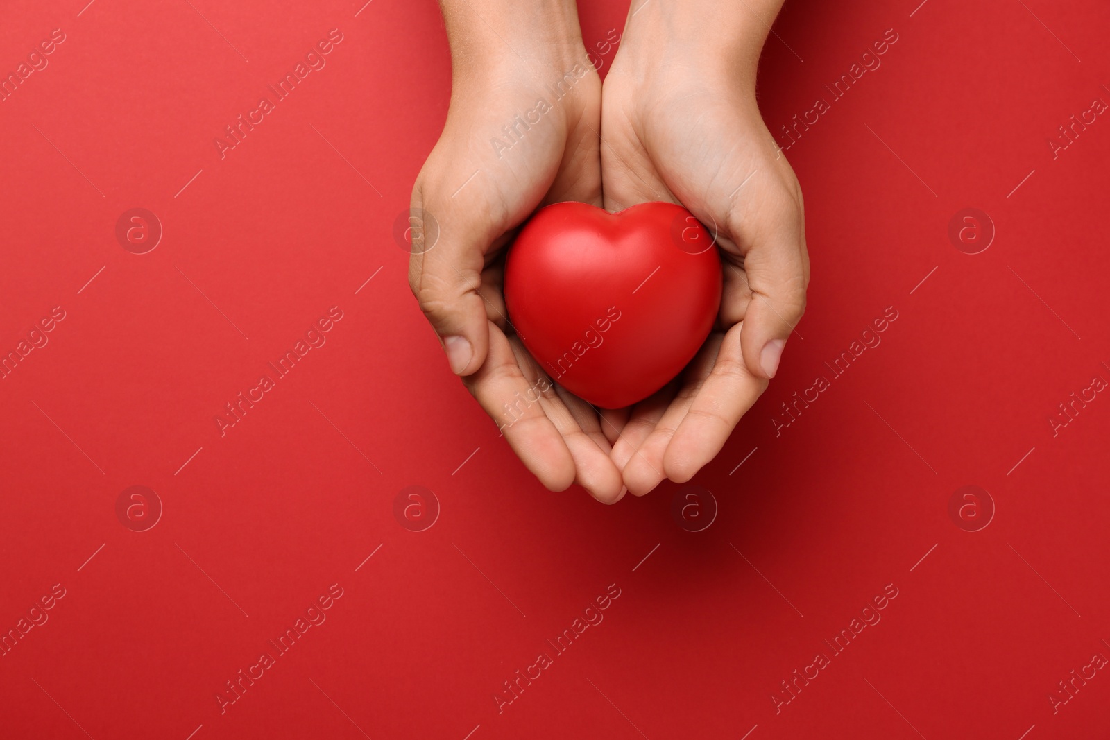 Photo of Woman holding decorative heart on red background, top view