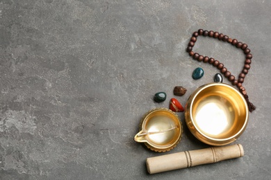 Flat lay composition with golden singing bowl on grey stone table, space for text. Sound healing