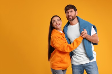 Photo of Happy couple dancing together on orange background, space for text