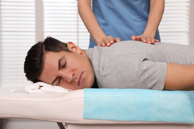 Orthopedist massaging man's back in clinic, closeup. Scoliosis treatment