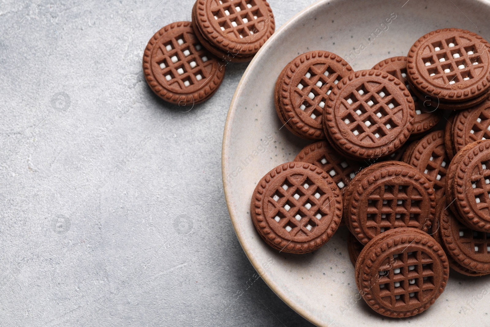 Photo of Tasty chocolate sandwich cookies with cream on light grey table, flat lay. Space for text