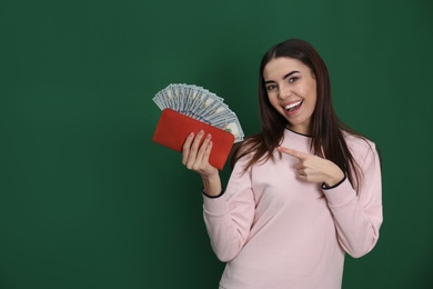 Photo of Young woman with money in wallet on color background. Space for text