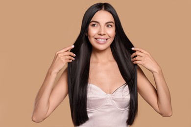 Portrait of beautiful young woman with healthy strong hair on beige background