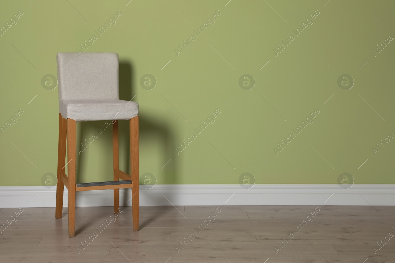 Photo of Stylish bar stool near light green wall indoors. Space for text