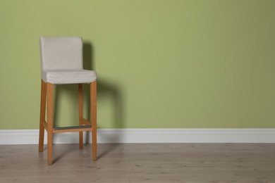 Stylish bar stool near light green wall indoors. Space for text