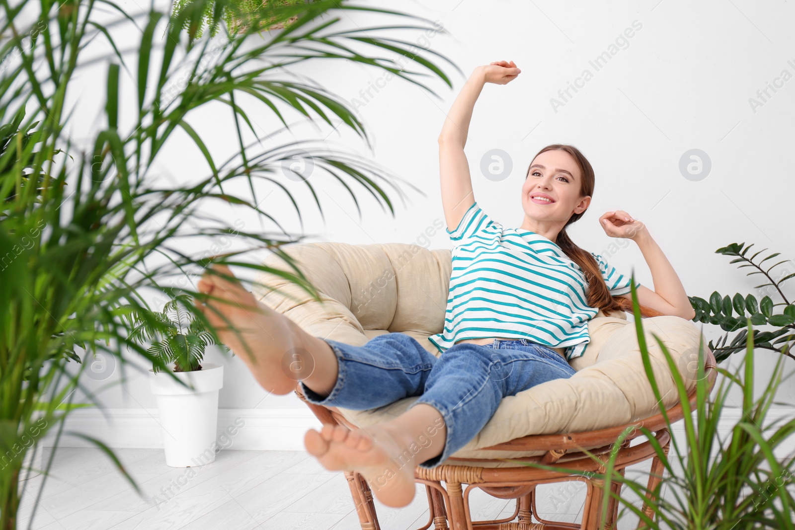 Photo of Young woman in room decorated with plants. Home design