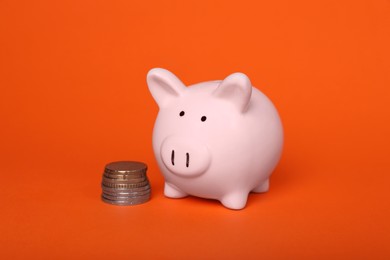 Photo of Ceramic piggy bank and coins on orange background. Financial savings