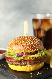 Photo of Burger with delicious patty, soda drink, french fries and sauce on table against gray background, closeup