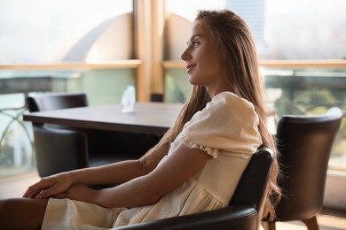 Beautiful young woman sitting on indoor terrace in cafe