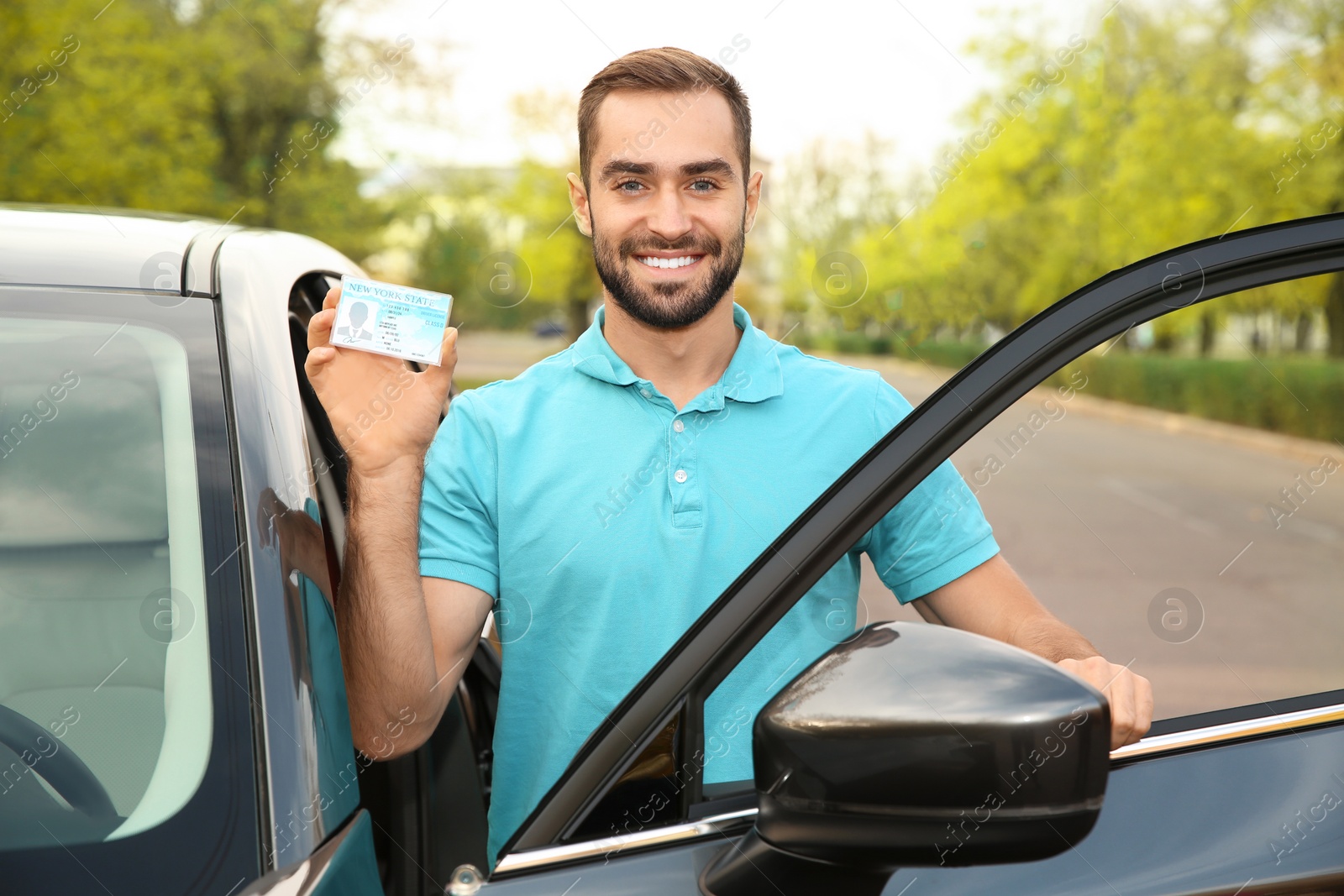 Photo of Young man holding driving license near open car