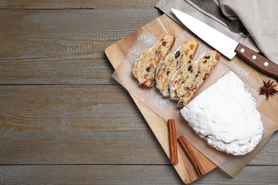 Photo of Traditional Christmas Stollen with icing sugar on wooden table, flat lay. Space for text