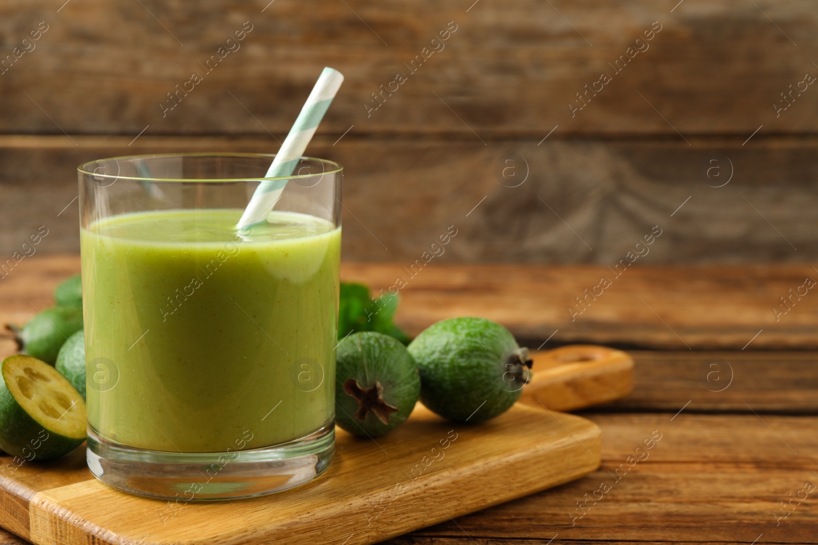 Photo of Fresh feijoa smoothie and fresh fruits on wooden table, closeup. Space for text