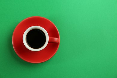 Cup of tasty coffee on green background, top view. Space for text