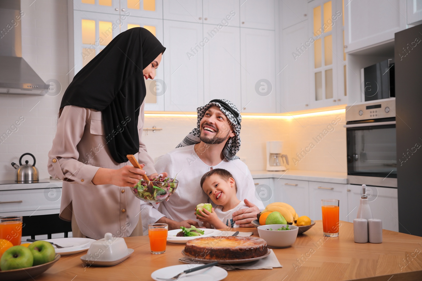 Photo of Happy Muslim family eating together in kitchen