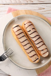 Tasty glazed eclairs served on wooden rustic table, top view