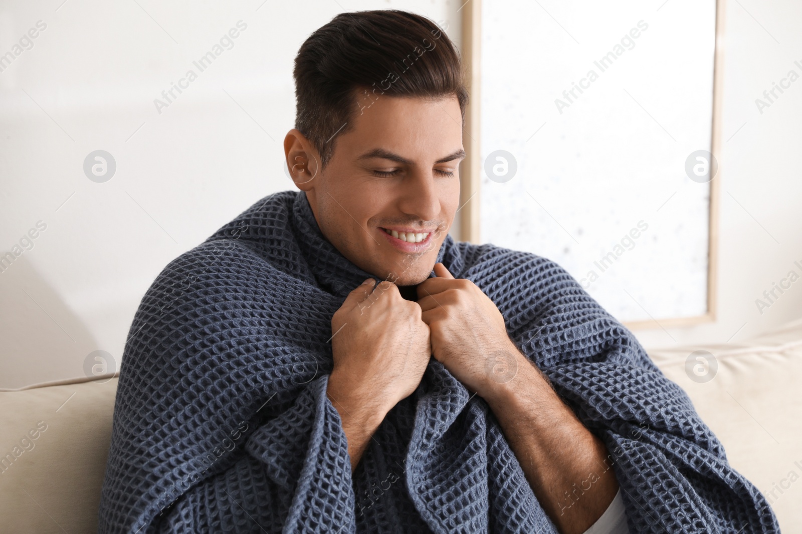 Photo of Man covered with warm dark blue plaid at home