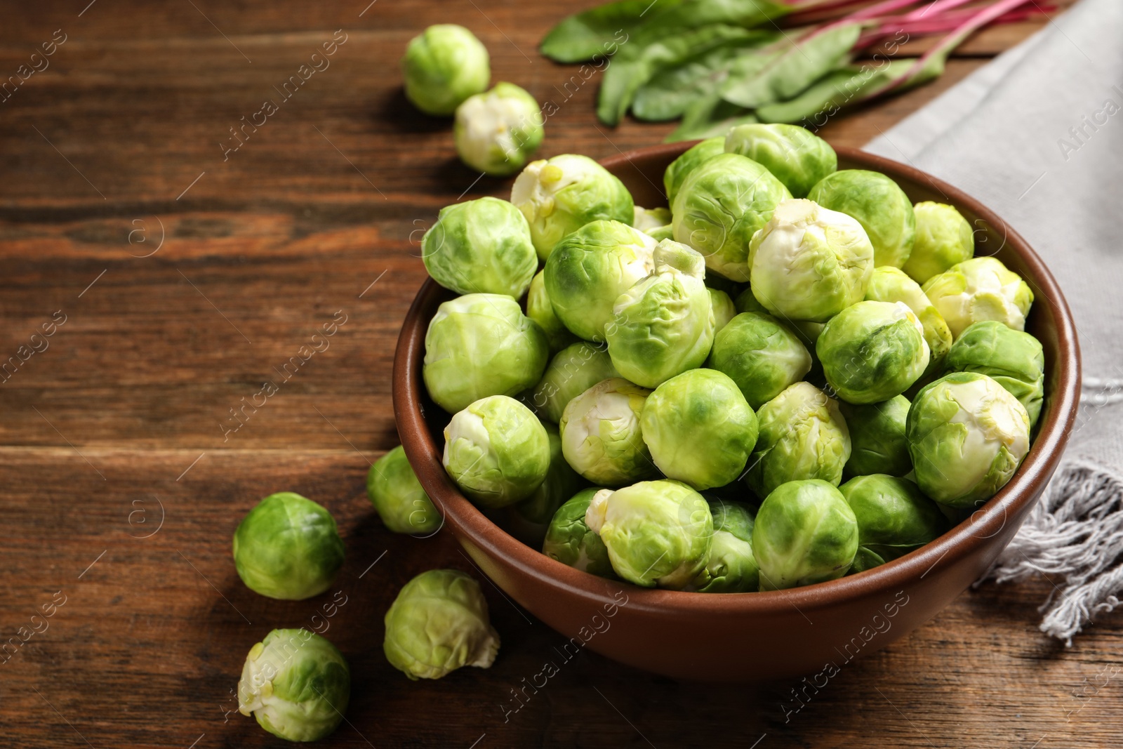 Photo of Bowl of fresh Brussels sprouts on wooden table. Space for text