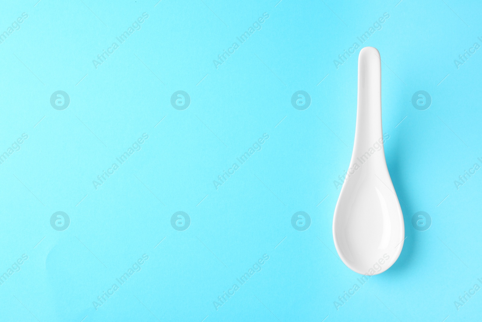 Photo of Miso soup spoon on blue background, top view. Space for text