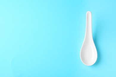 Photo of Miso soup spoon on blue background, top view. Space for text