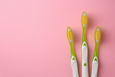 Toothbrushes on pink background, flat lay. Space for text