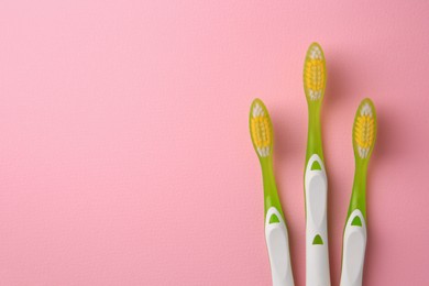 Photo of Toothbrushes on pink background, flat lay. Space for text