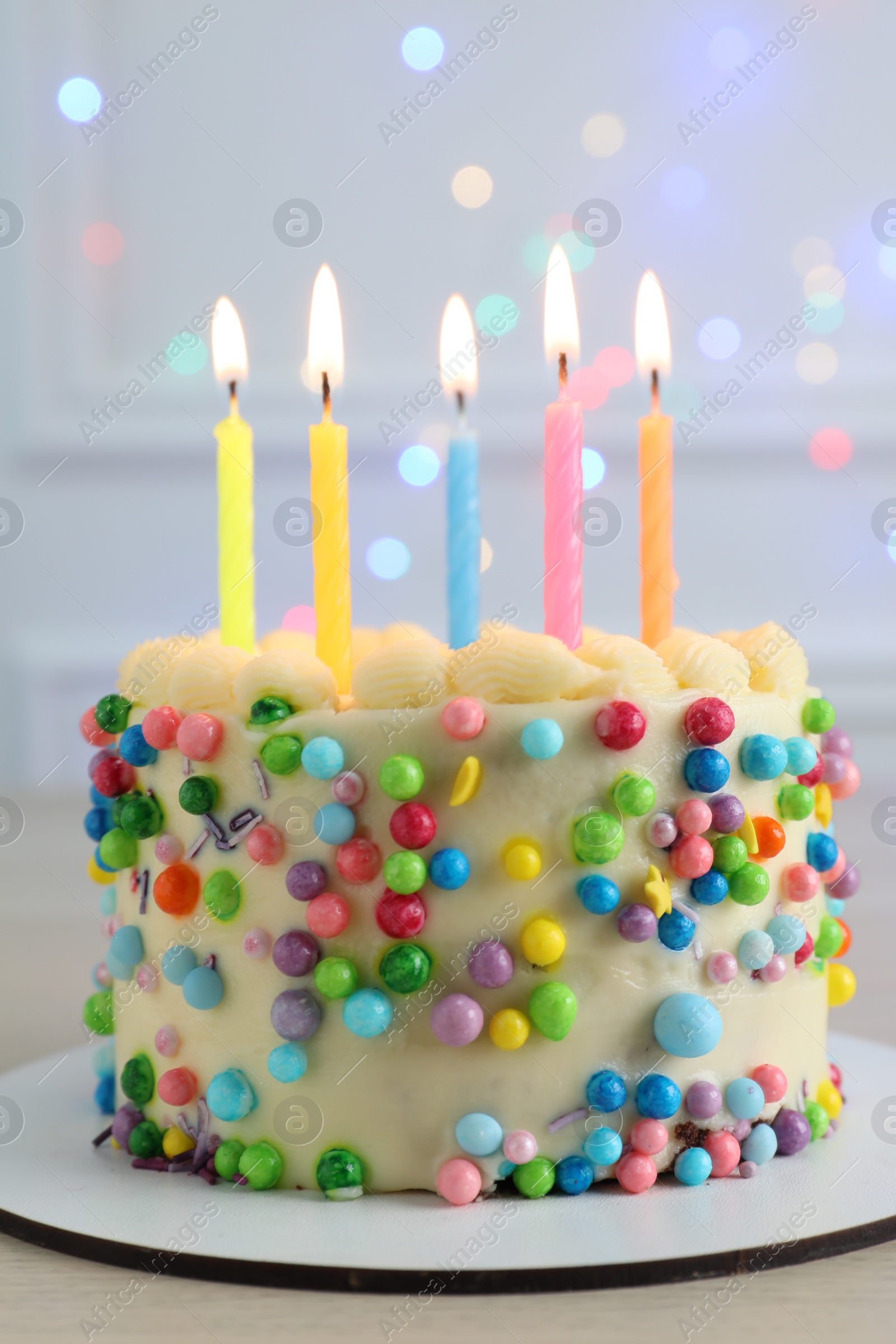 Photo of Cute bento cake with tasty cream and burning candles on white wooden table