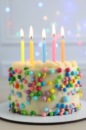 Cute bento cake with tasty cream and burning candles on white wooden table