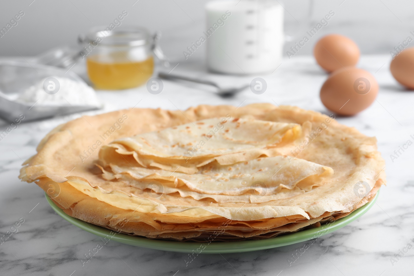 Photo of Delicious crepes on white marble table, closeup