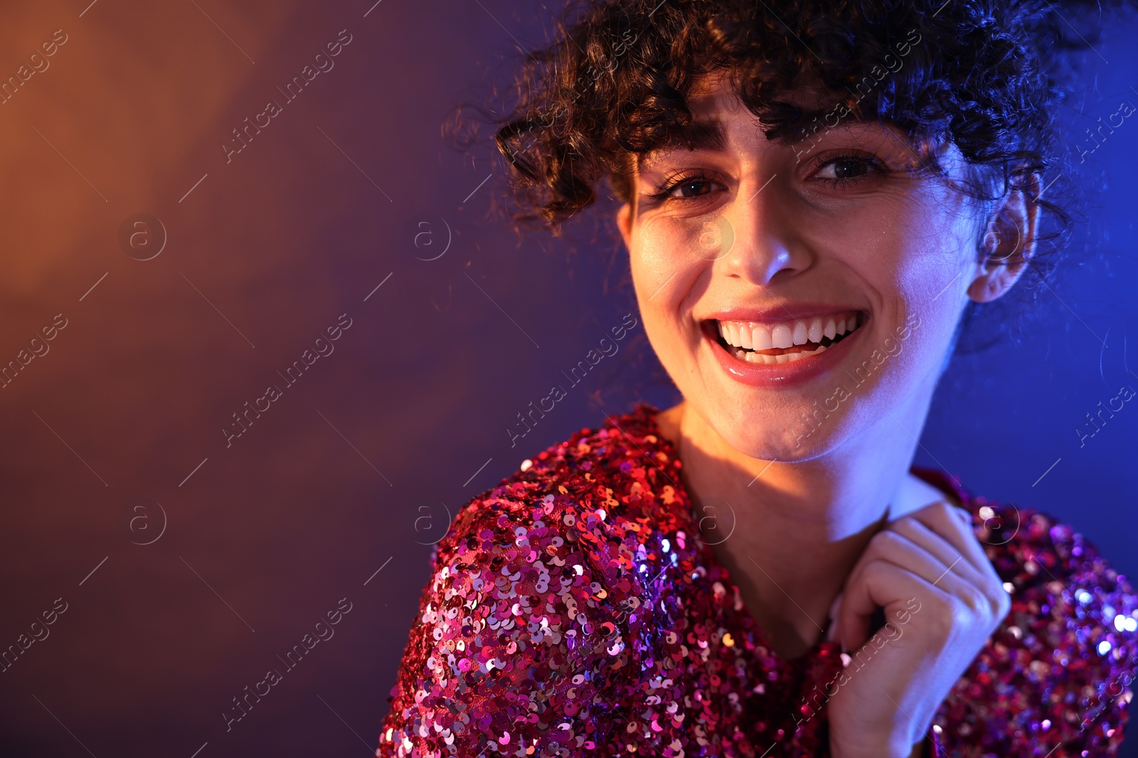 Photo of Beautiful young woman posing on color background in neon lights