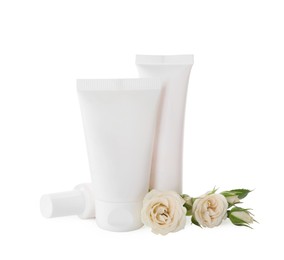 Photo of Tubes of hand cream and roses on white background