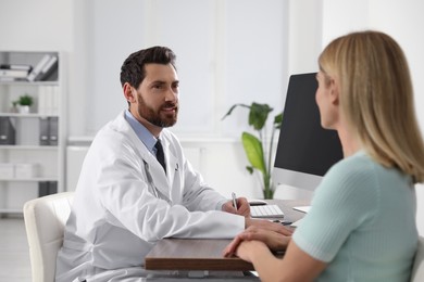 Photo of Doctor consulting patient at wooden table in clinic