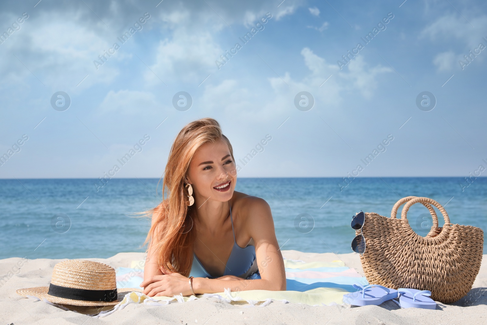 Photo of Beautiful woman with bag and other beach stuff on sand near sea