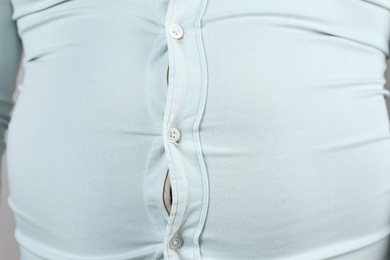 Photo of Overweight man with large belly in tight shirt , closeup