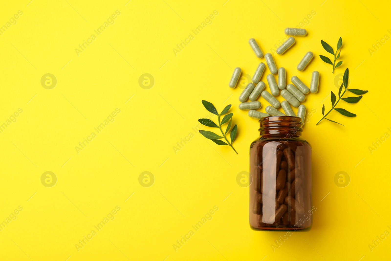 Photo of Vitamin pills, branches and bottle on yellow background, flat lay. Space for text