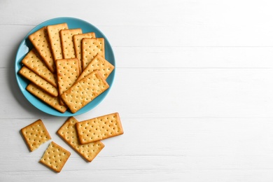 Photo of Delicious crackers on white wooden table, flat lay. Space for text