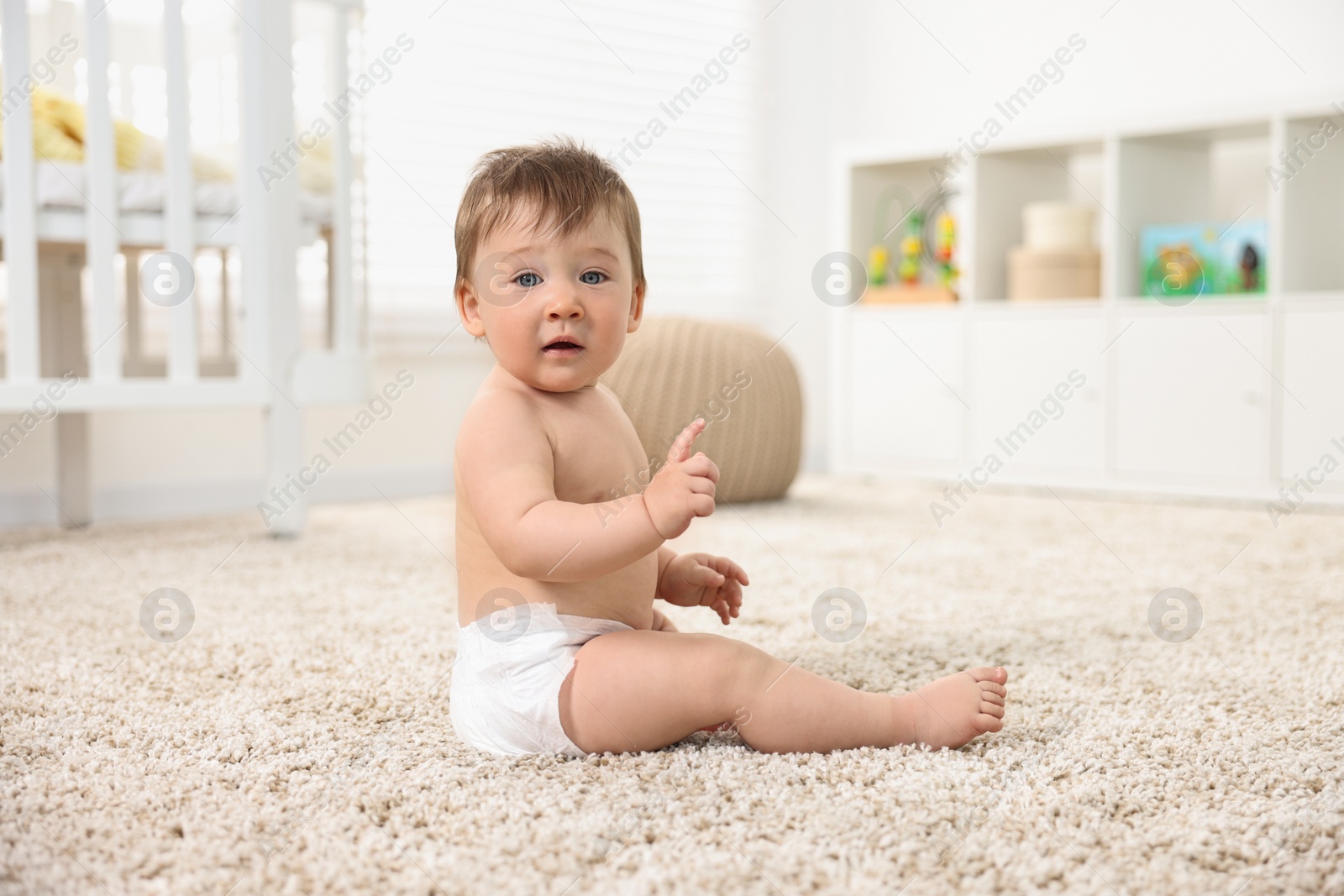 Photo of Cute baby boy sitting on carpet at home