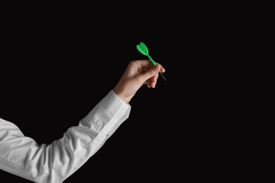 Businesswoman holding green dart on black background, closeup. Space for text