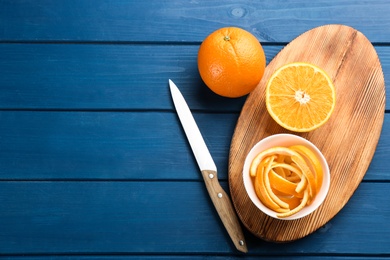 Orange fruits with peels on blue wooden table, flat lay. Space for text