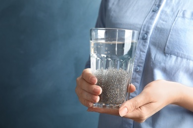 Photo of Woman holding glass of water with chia seeds on color background, closeup. Space for text