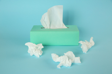 Photo of Used paper tissues and box on light blue background