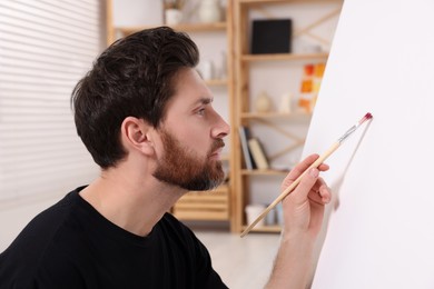 Photo of Man painting on white canvas in studio