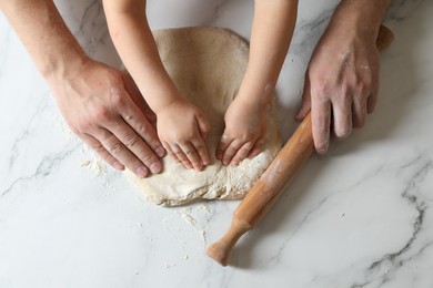 Photo of Father and child making dough at white table, top view