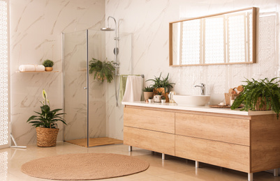 Stylish bathroom interior with countertop, shower stall and houseplants. Design idea