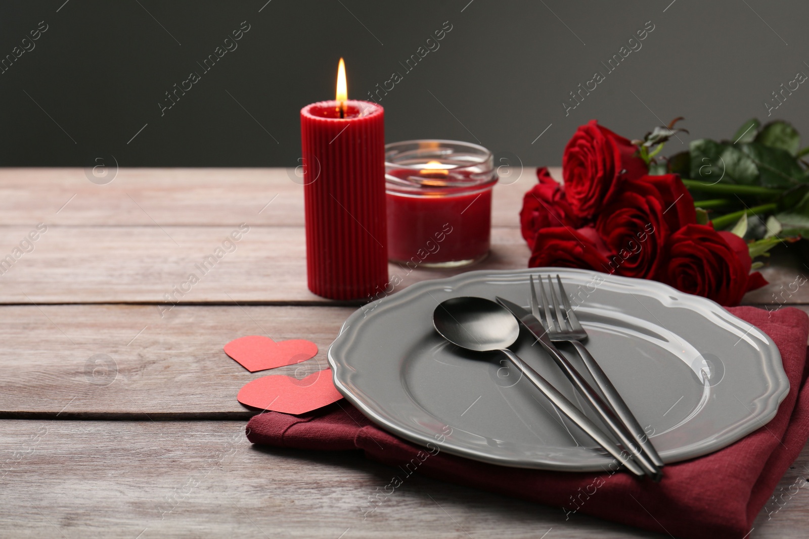 Photo of Romantic place setting with red roses, candles and decorative hearts on wooden table, space for text. St. Valentine's day dinner