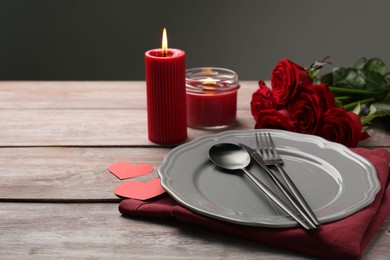 Photo of Romantic place setting with red roses, candles and decorative hearts on wooden table, space for text. St. Valentine's day dinner