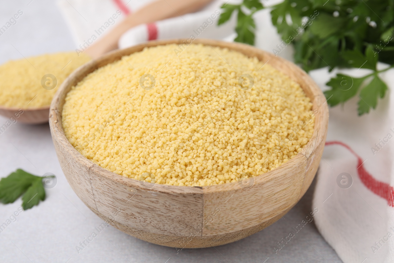 Photo of Raw couscous in wooden bowl on table, closeup