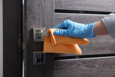 Photo of Woman wiping door handle with rag, closeup